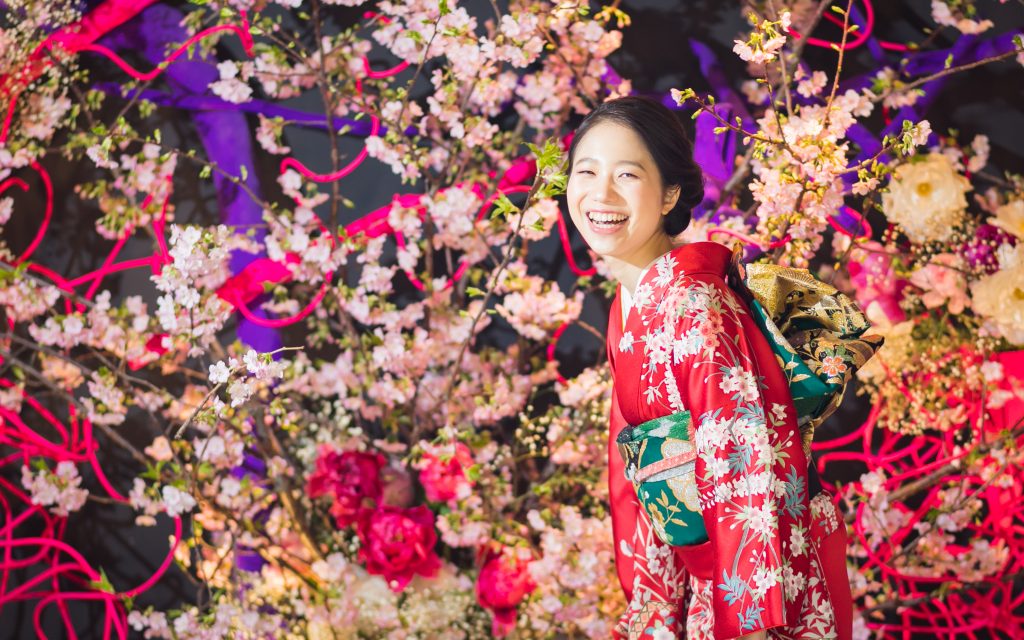 お花をバックに笑顔の振袖姿の女性